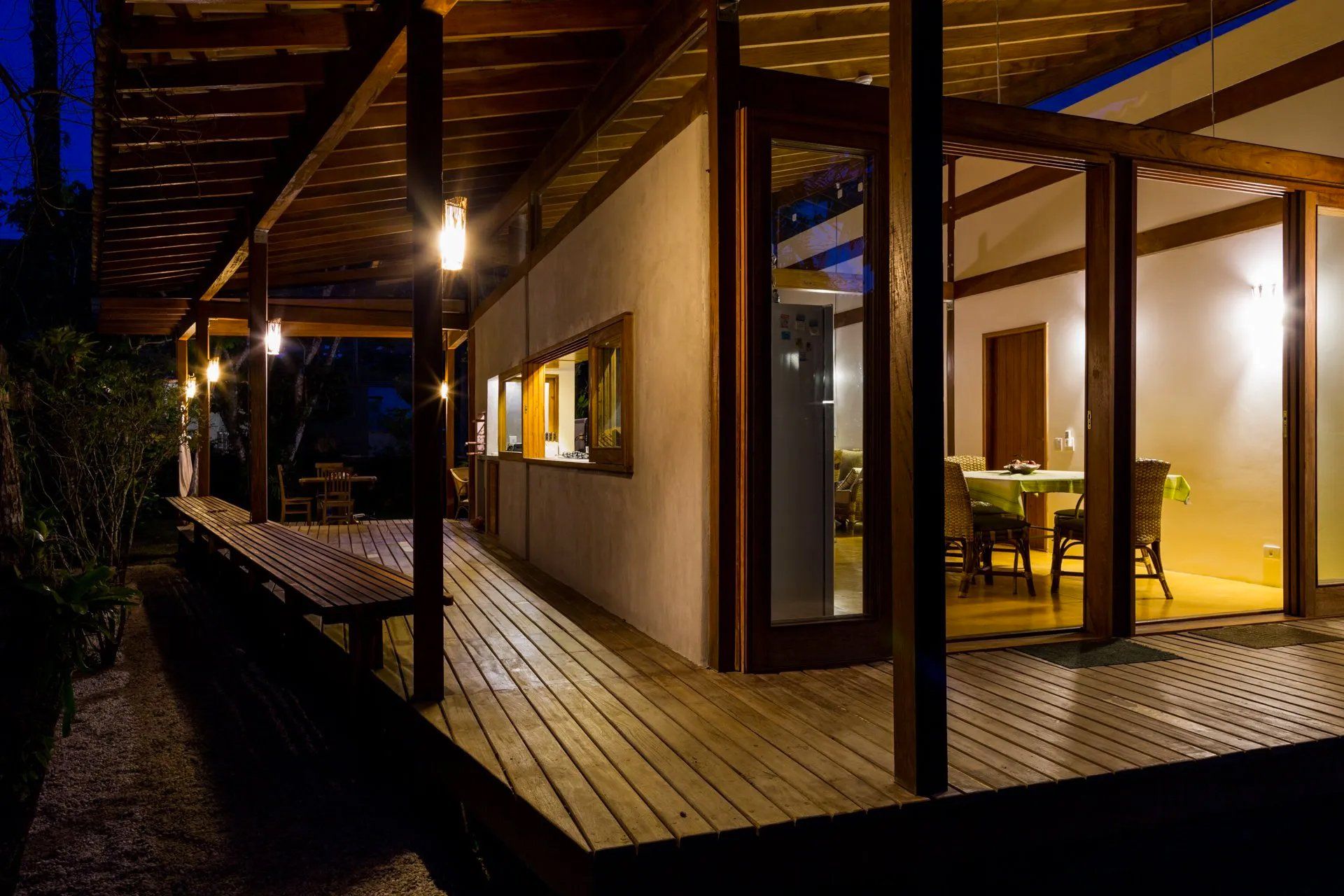 Uma casa com deck de madeira e portas de vidro deslizantes à noite