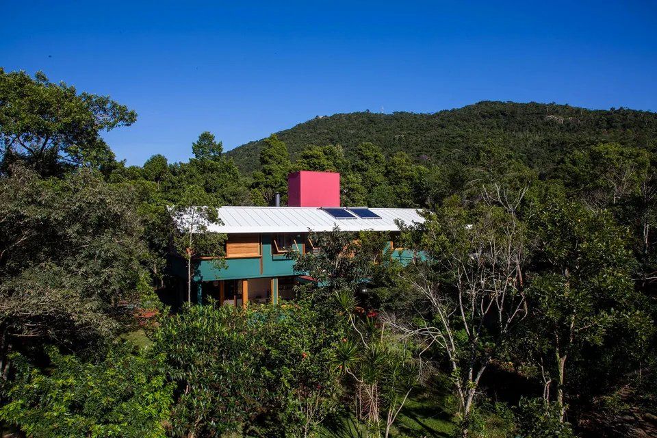Uma casa colorida é cercada por árvores em uma encosta.