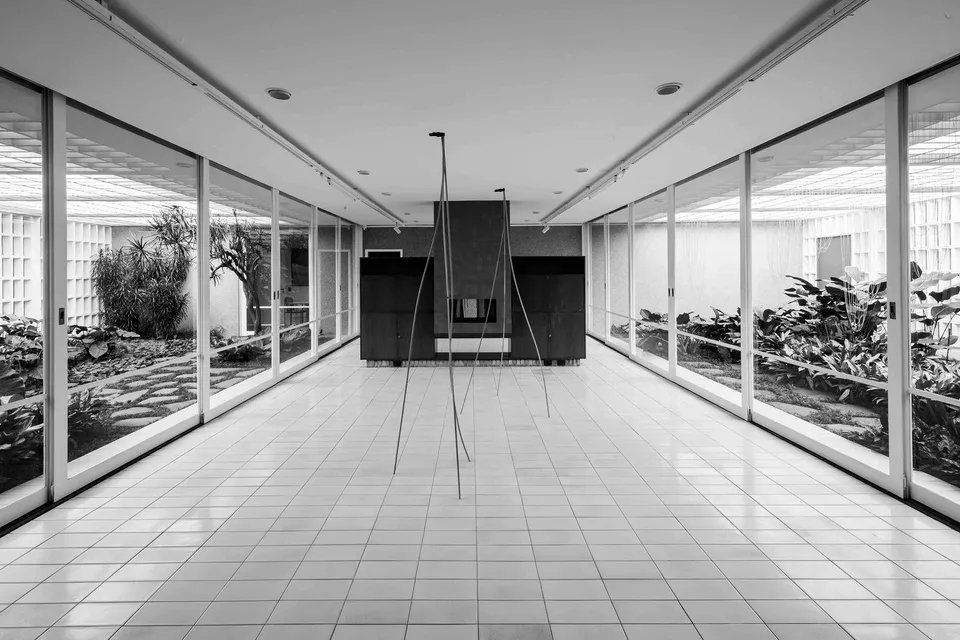 Uma foto em preto e branco de um longo corredor com muitas janelas.