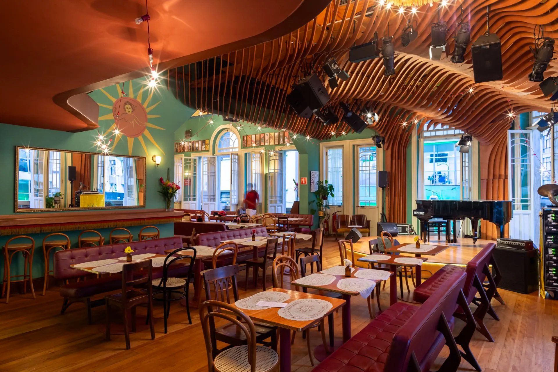 Uma grande sala de jantar com mesas e cadeiras e um piano.