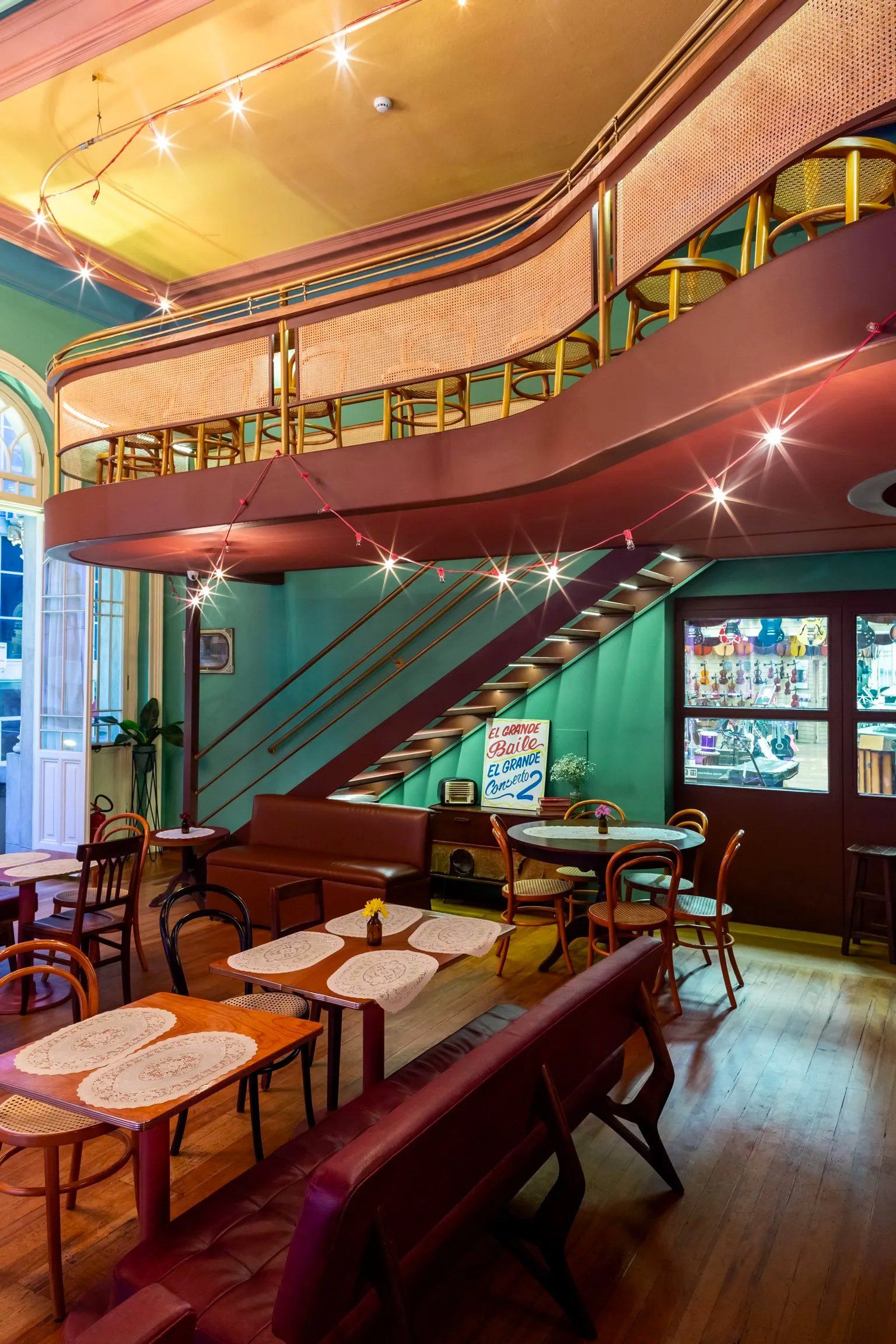 Um restaurante com mesas e cadeiras e escadas que levam ao segundo andar.