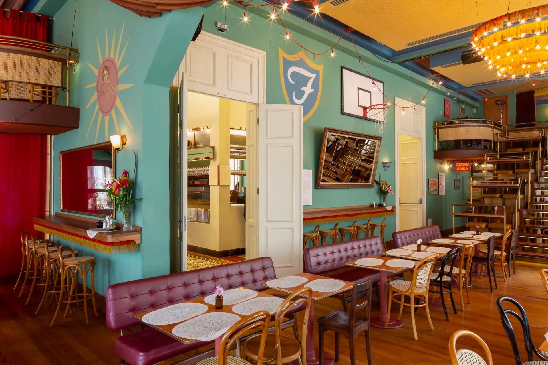 Um restaurante com mesas e cadeiras e uma quadra de basquete na parede.