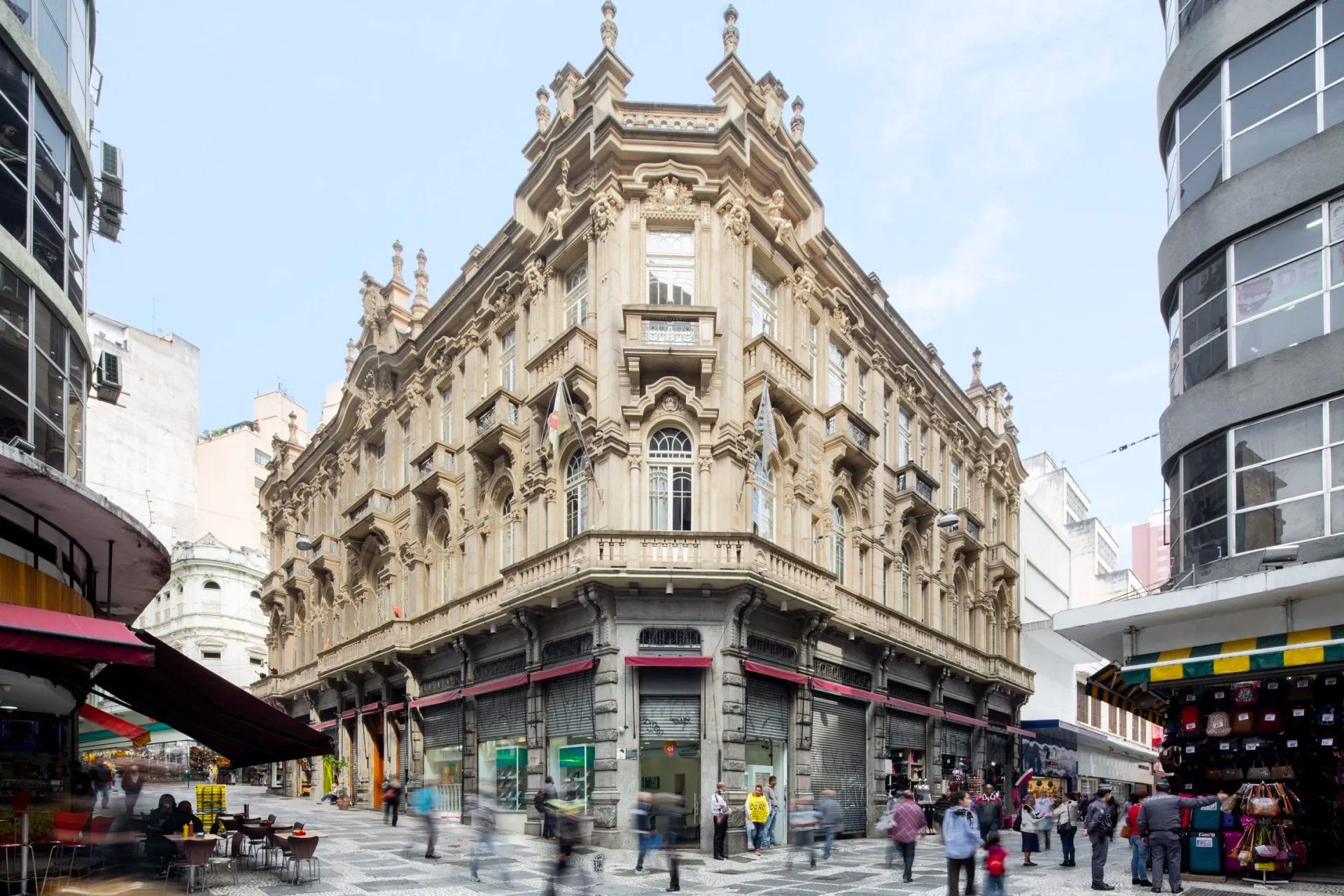 Um grande edifício com muitas janelas fica na esquina de uma rua da cidade.
