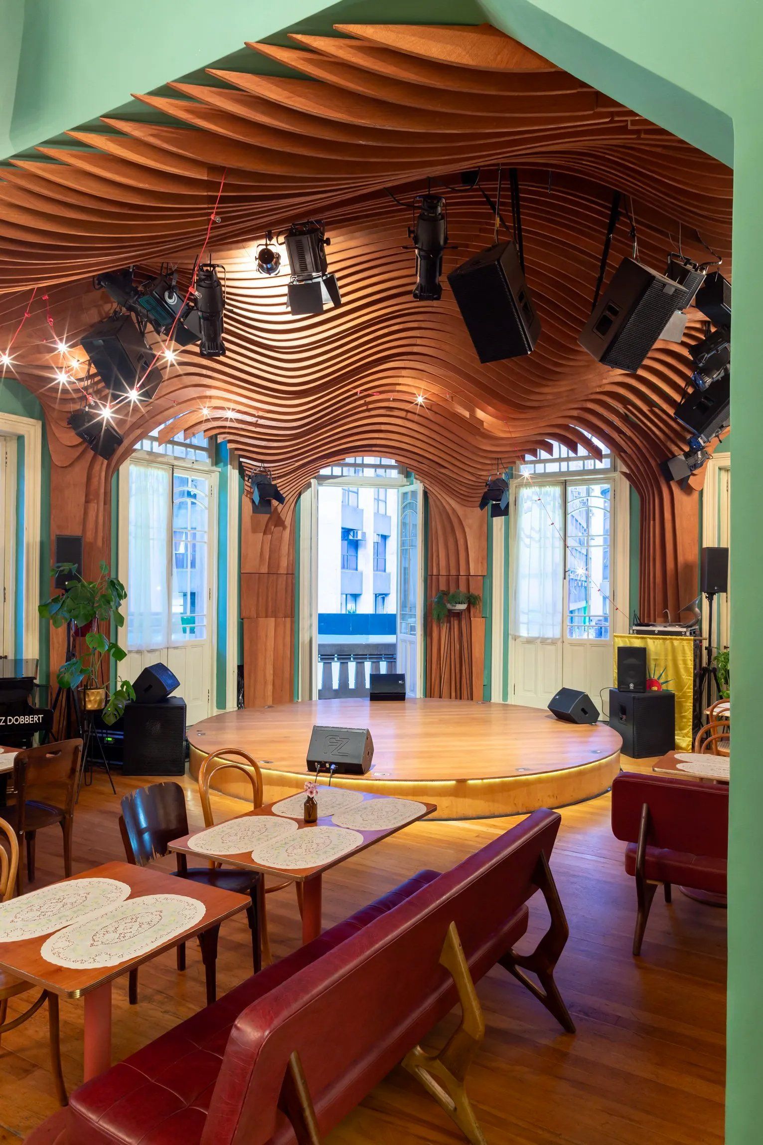 Há um palco no meio da sala com mesas e cadeiras.