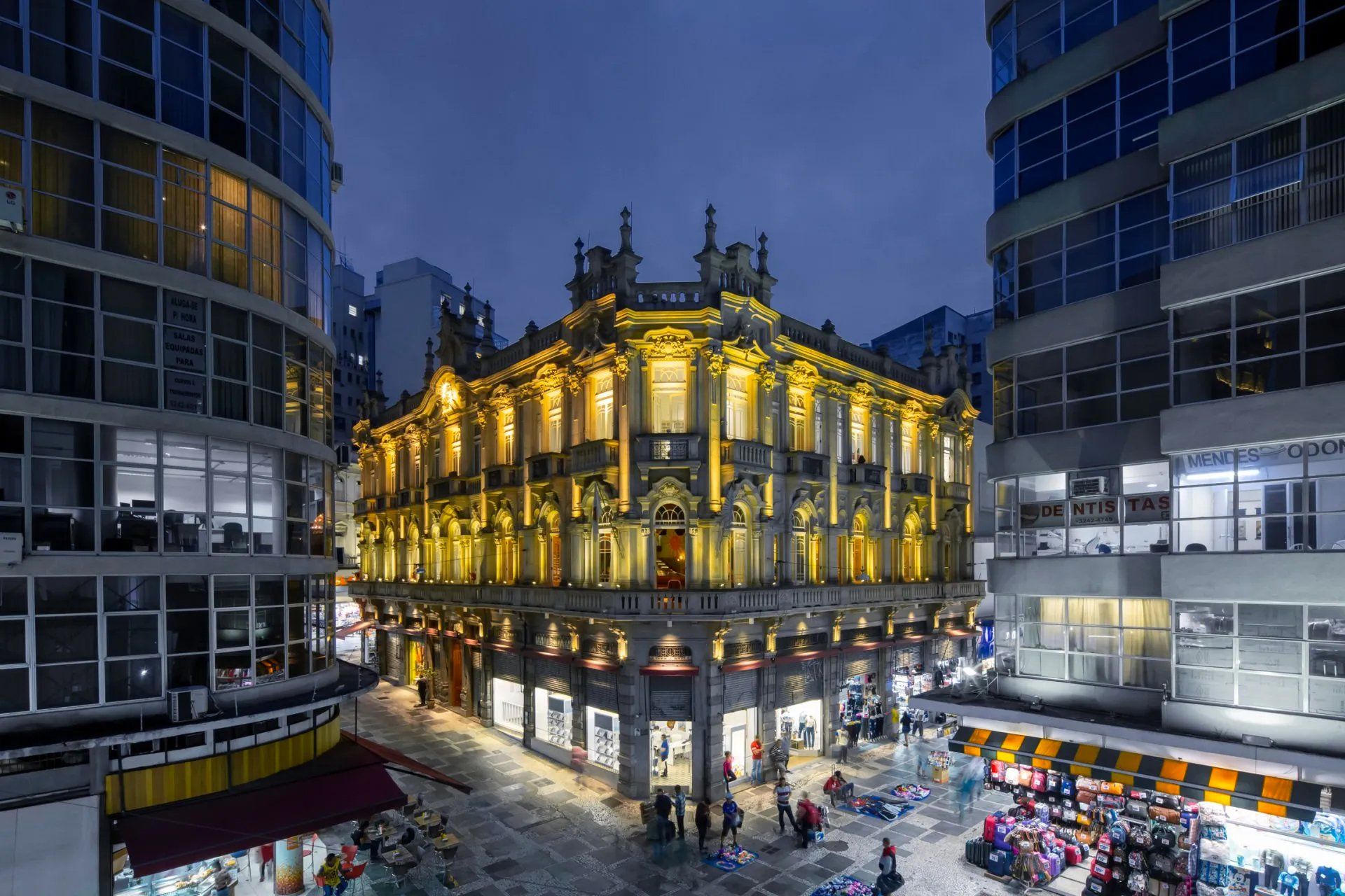 Um grande edifício com muitas janelas fica no meio de uma cidade à noite.