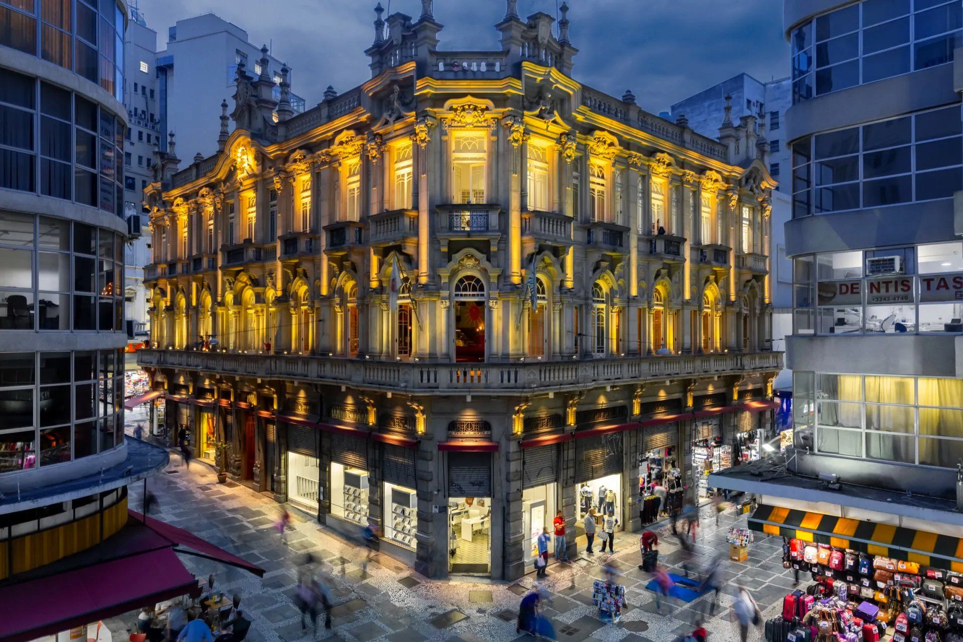 Um grande edifício com muitas janelas fica iluminado à noite.