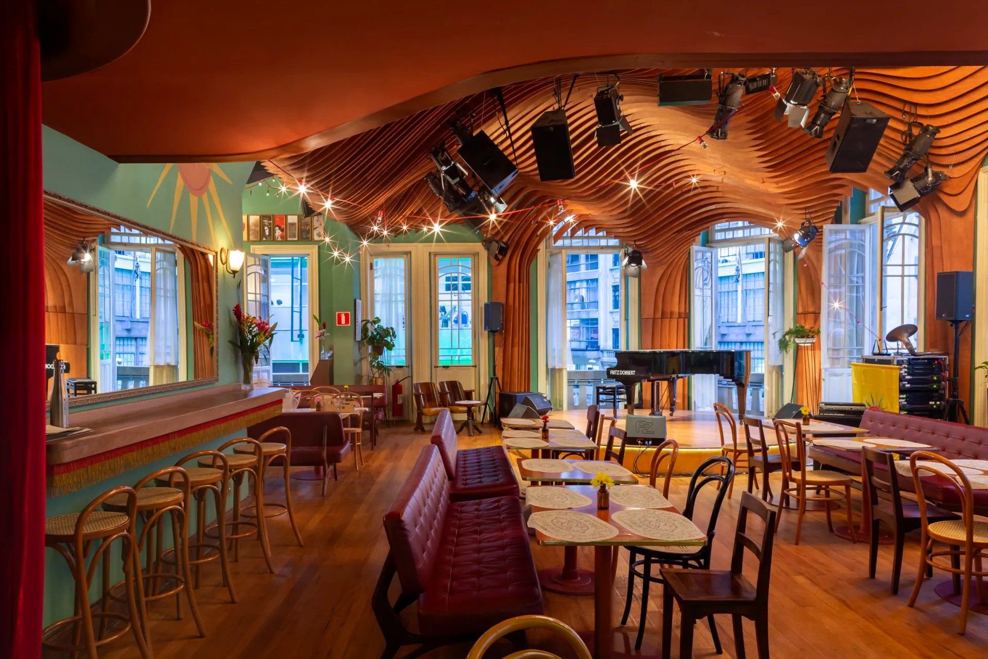 Uma grande sala com mesas e cadeiras e um piano.