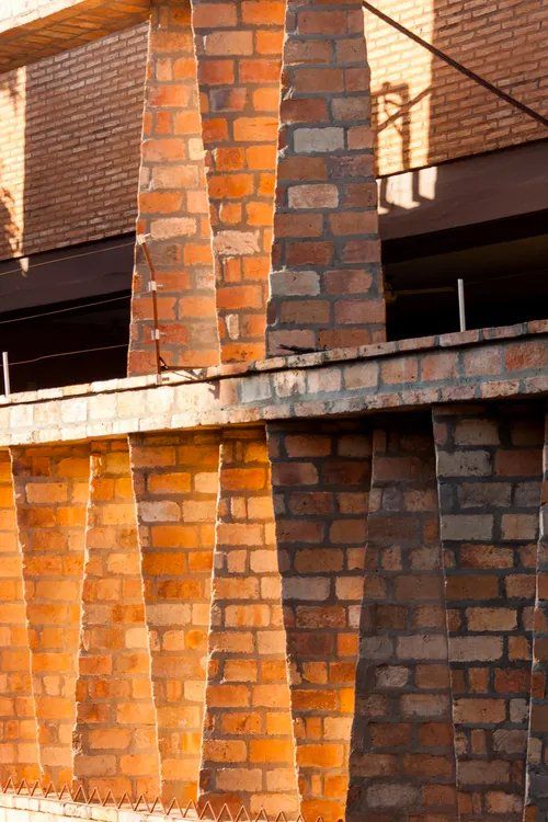 Uma fileira de chaminés de tijolos está sendo construída na lateral de um prédio.