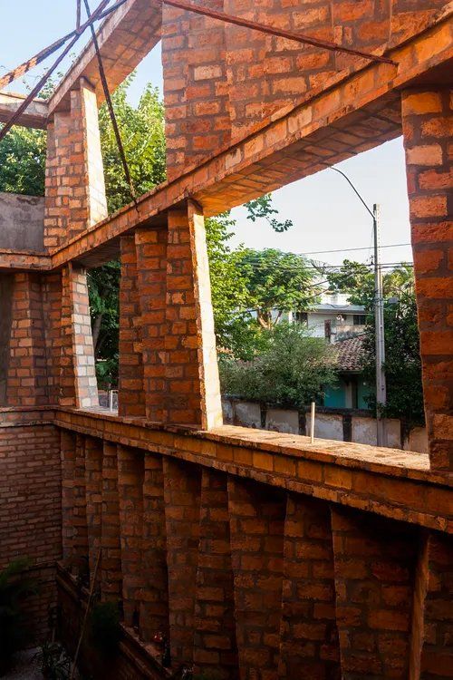 Uma parede de tijolos com muitas janelas e árvores ao fundo.