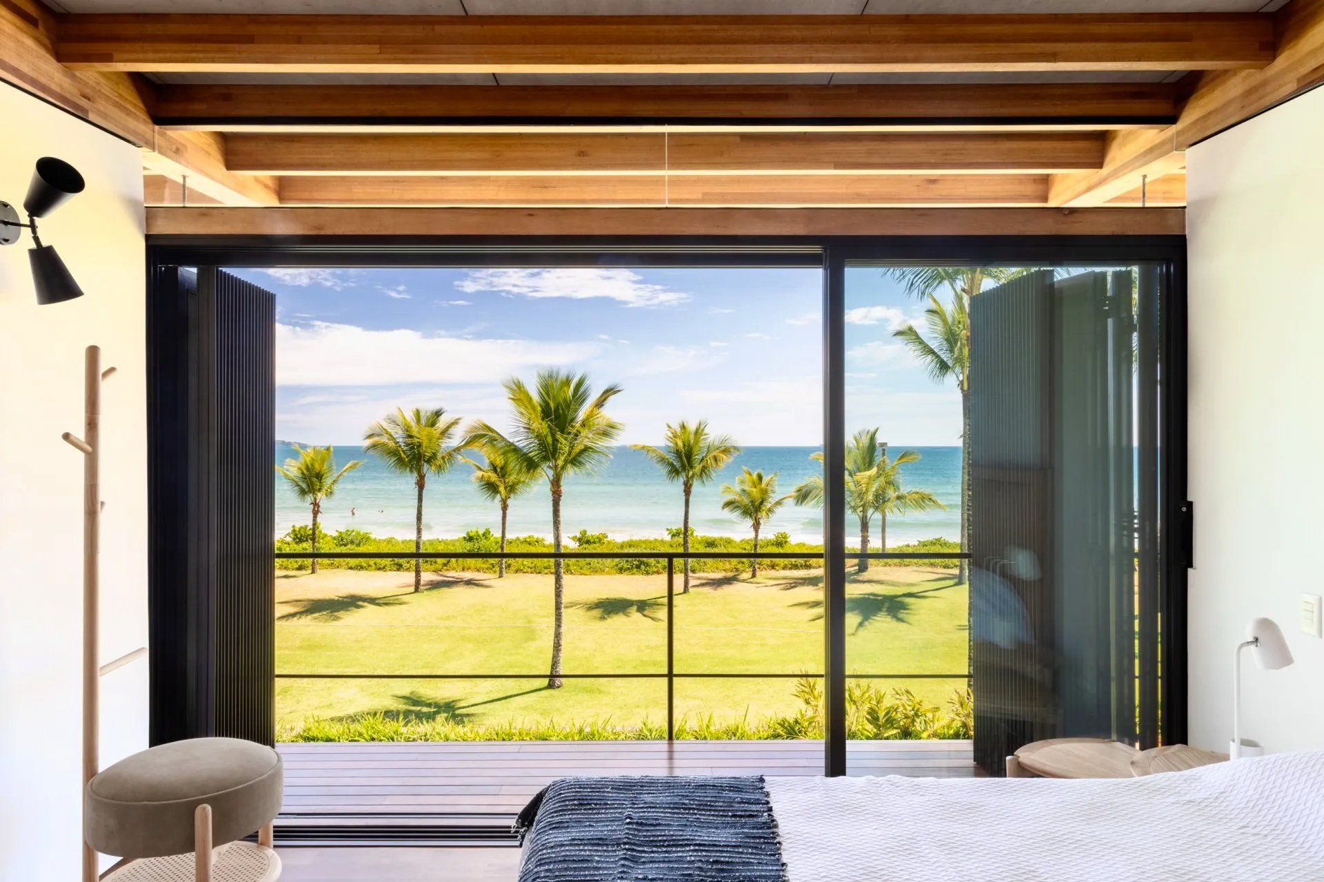 Um quarto com uma grande janela com vista para o mar e palmeiras.