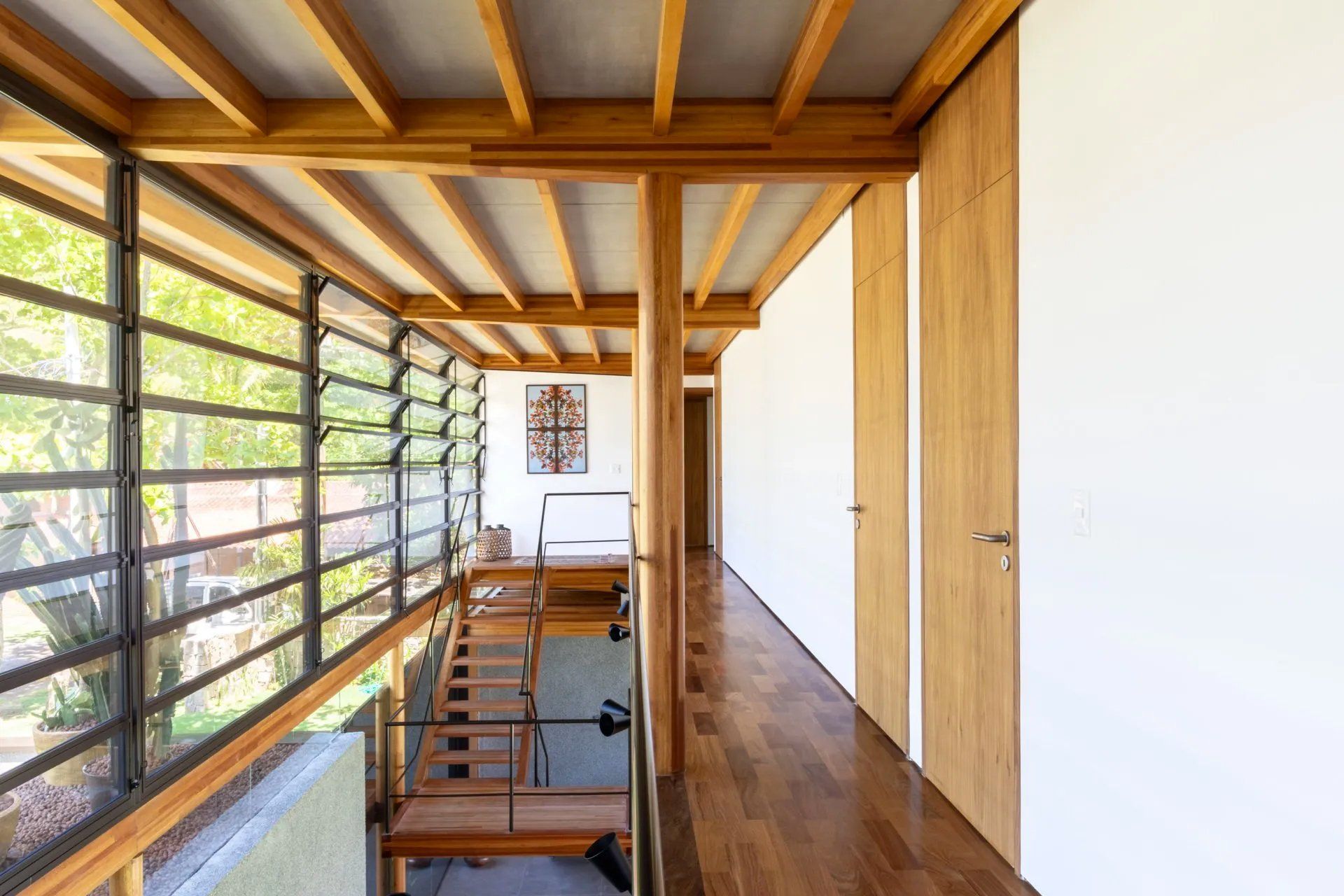 Um corredor em uma casa com piso de madeira e escadas