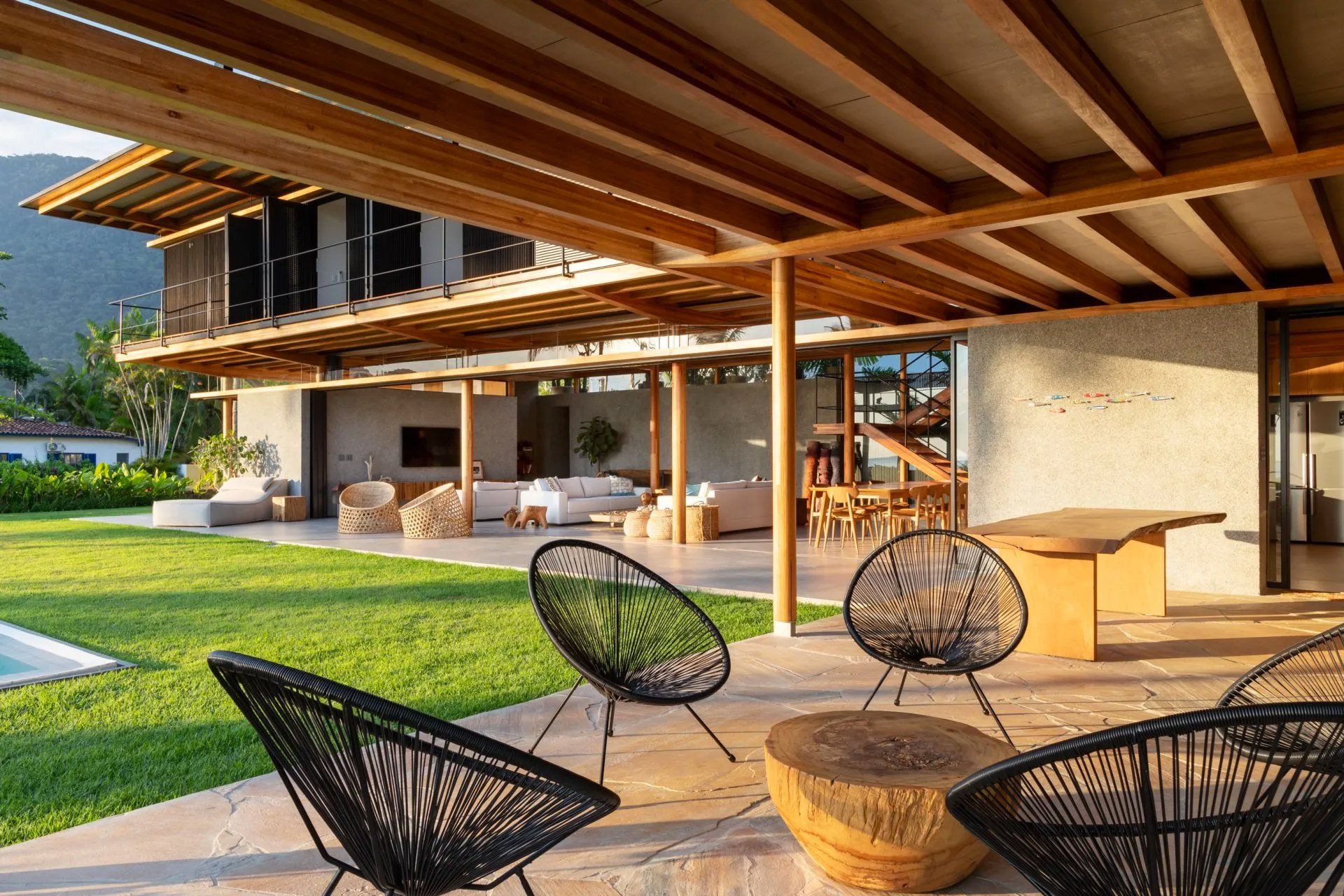 Um pátio com cadeiras e mesas em frente a uma casa grande.