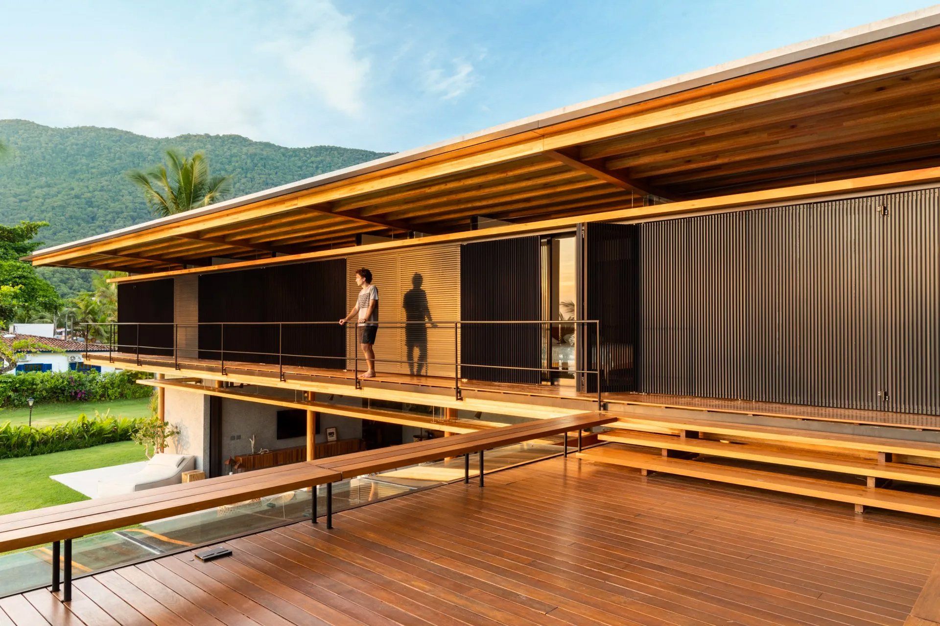 Algumas pessoas estão em um deck de madeira em frente a uma casa.