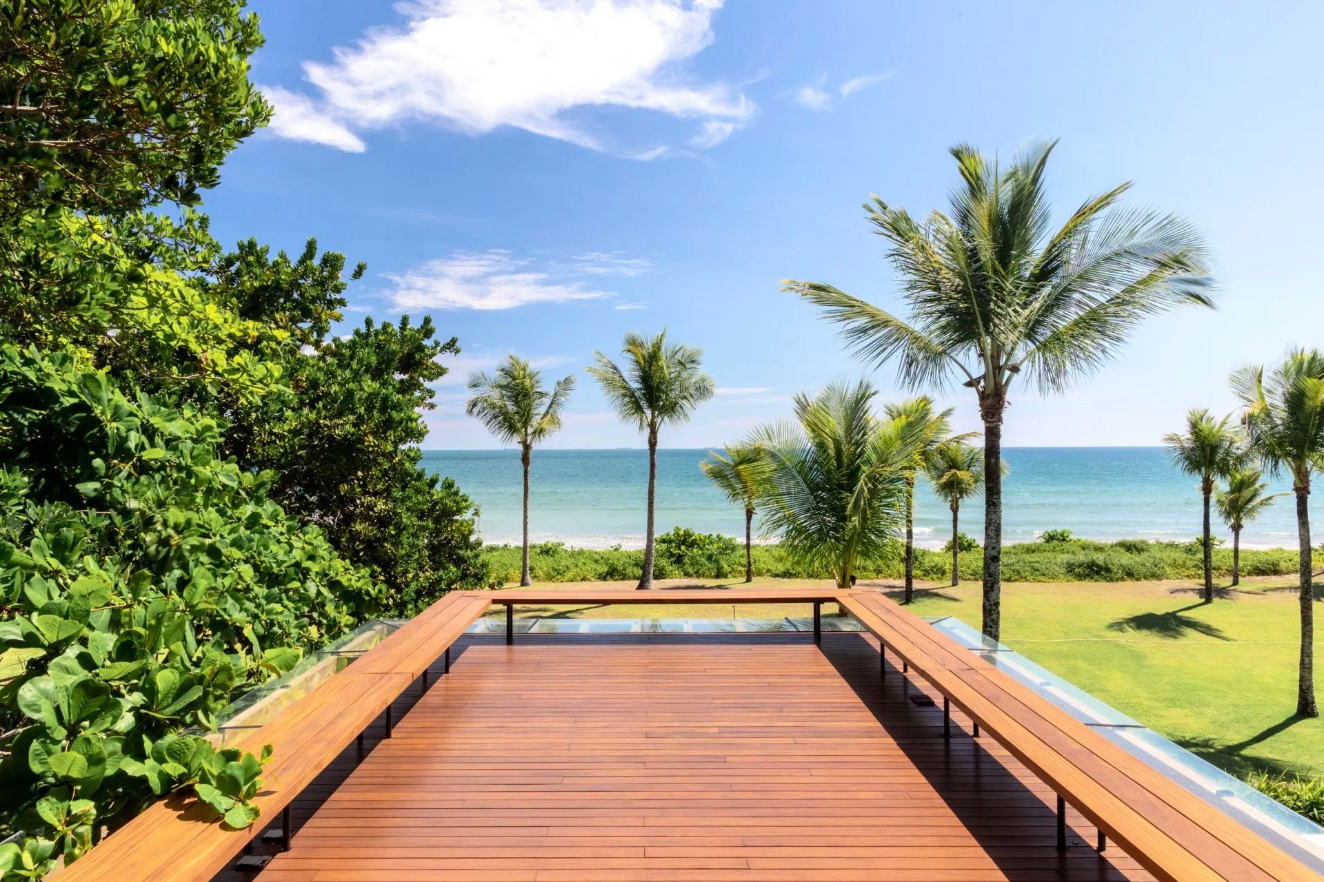 Um deck de madeira com vista para o mar e palmeiras