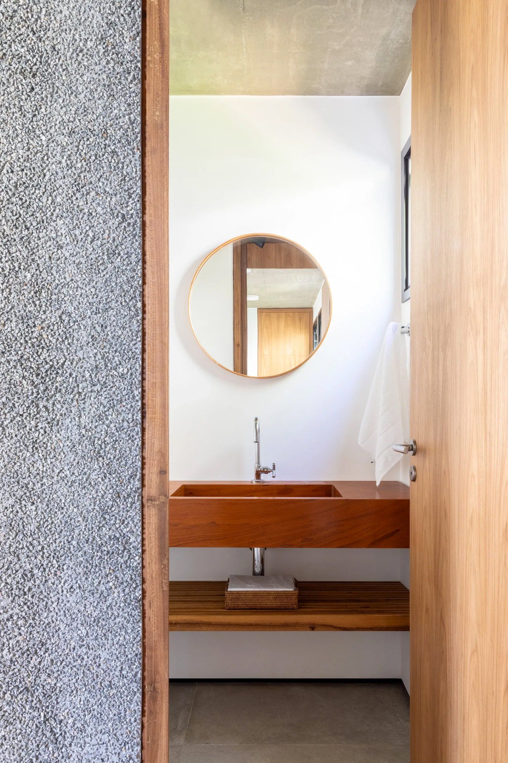 Um banheiro com pia de madeira e espelho redondo.