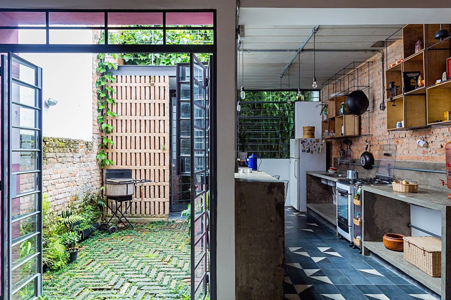 Uma cozinha com parede de tijolos e porta de correr de vidro que dá acesso a um quintal.