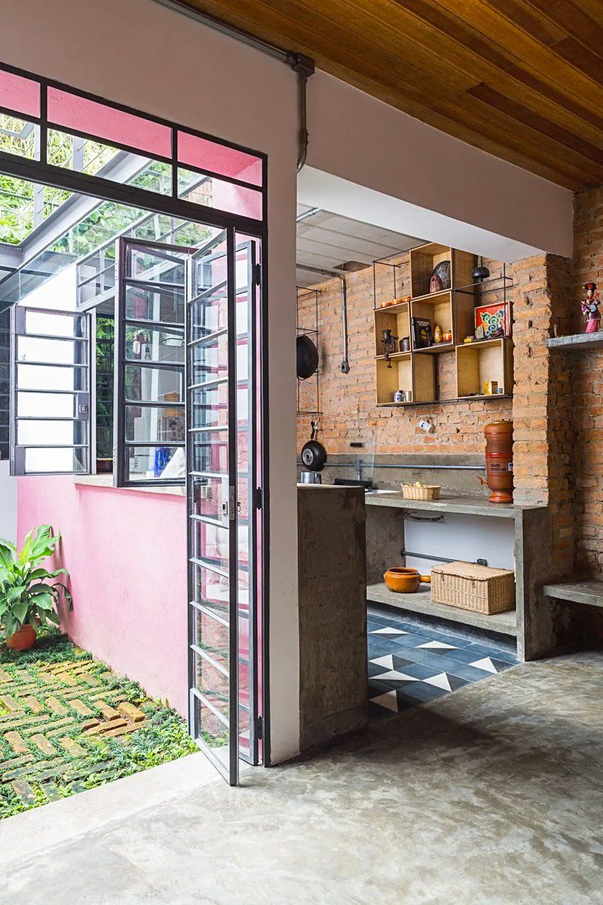 Uma cozinha com parede rosa e parede de tijolos.