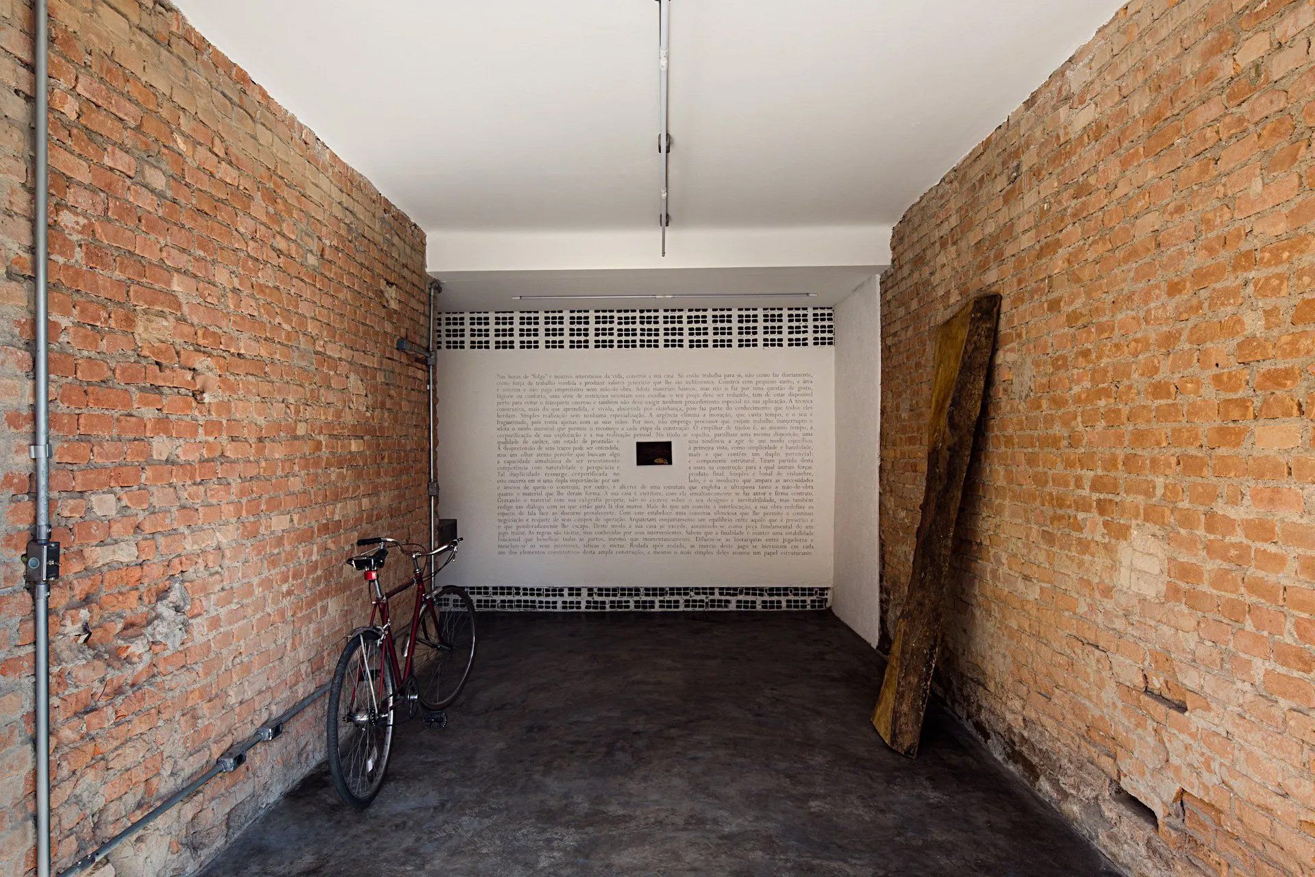 Uma bicicleta está estacionada em uma garagem próxima a uma parede de tijolos.