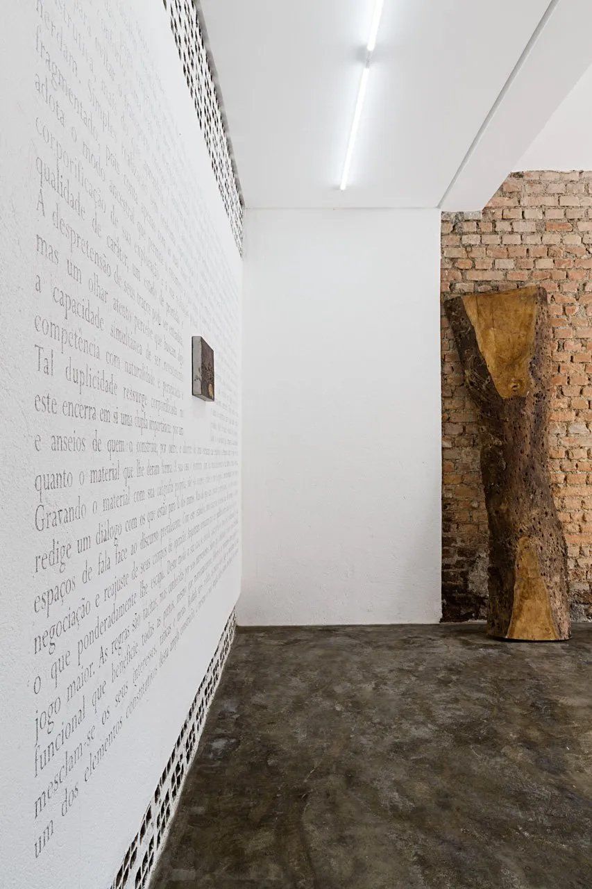 Uma sala com uma parede de tijolos e uma parede branca com algo escrito.