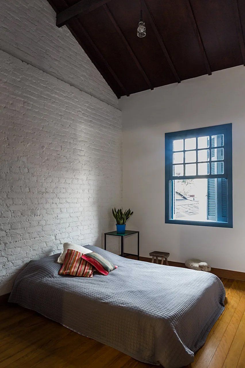 Um quarto com cama e janela com persianas azuis.