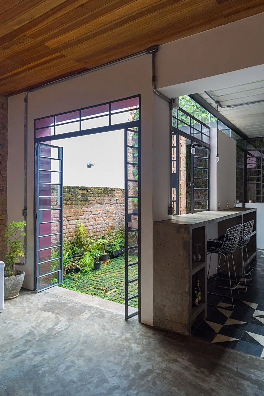 Uma sala com parede de tijolos e uma porta que dá para um jardim.