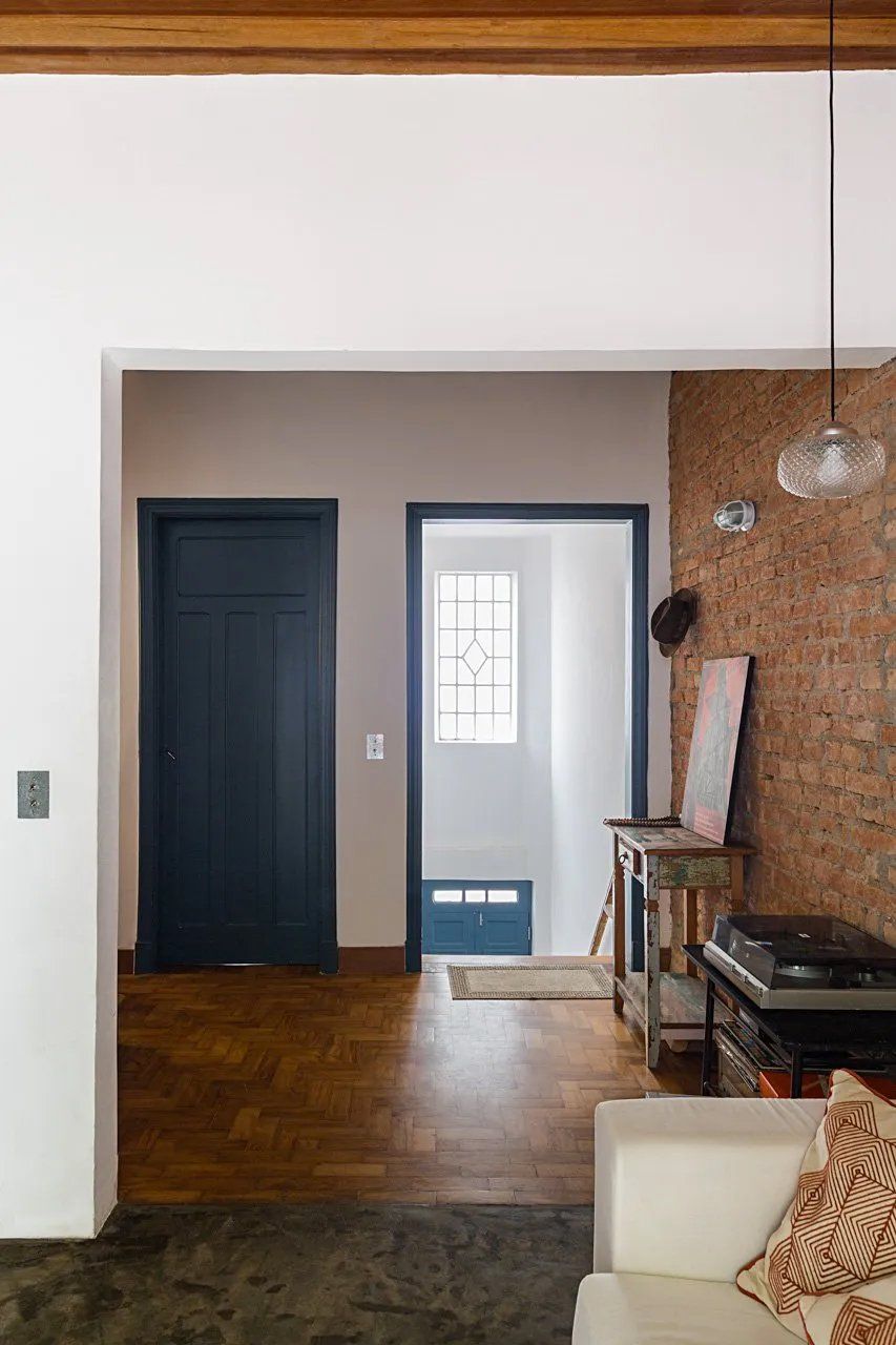 Uma sala com sofá, mesa, porta e parede de tijolos.