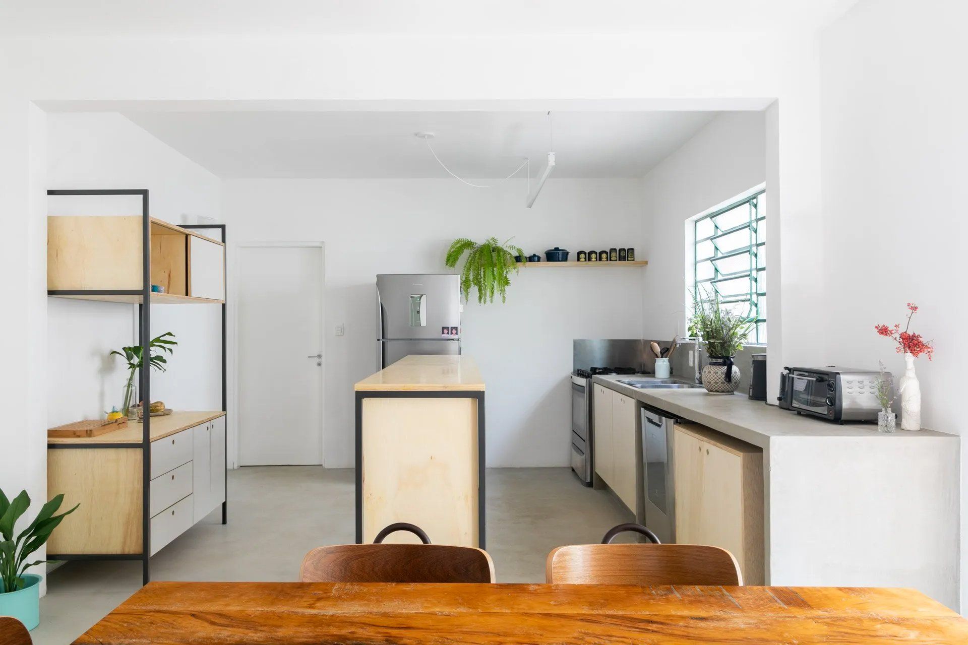 Uma cozinha com mesa e cadeiras de madeira e geladeira.