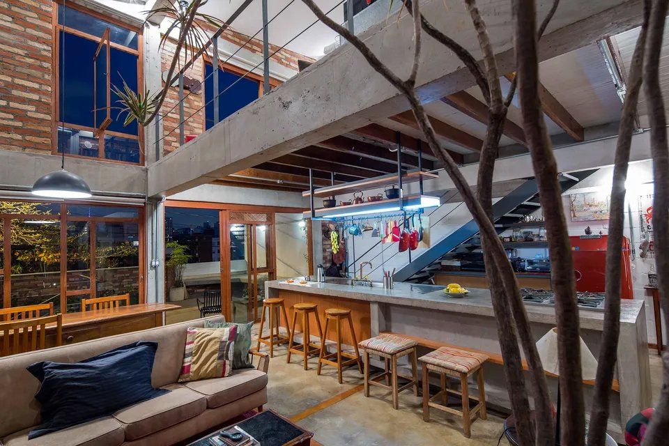 Uma sala de estar com sofá, bancos e cozinha.