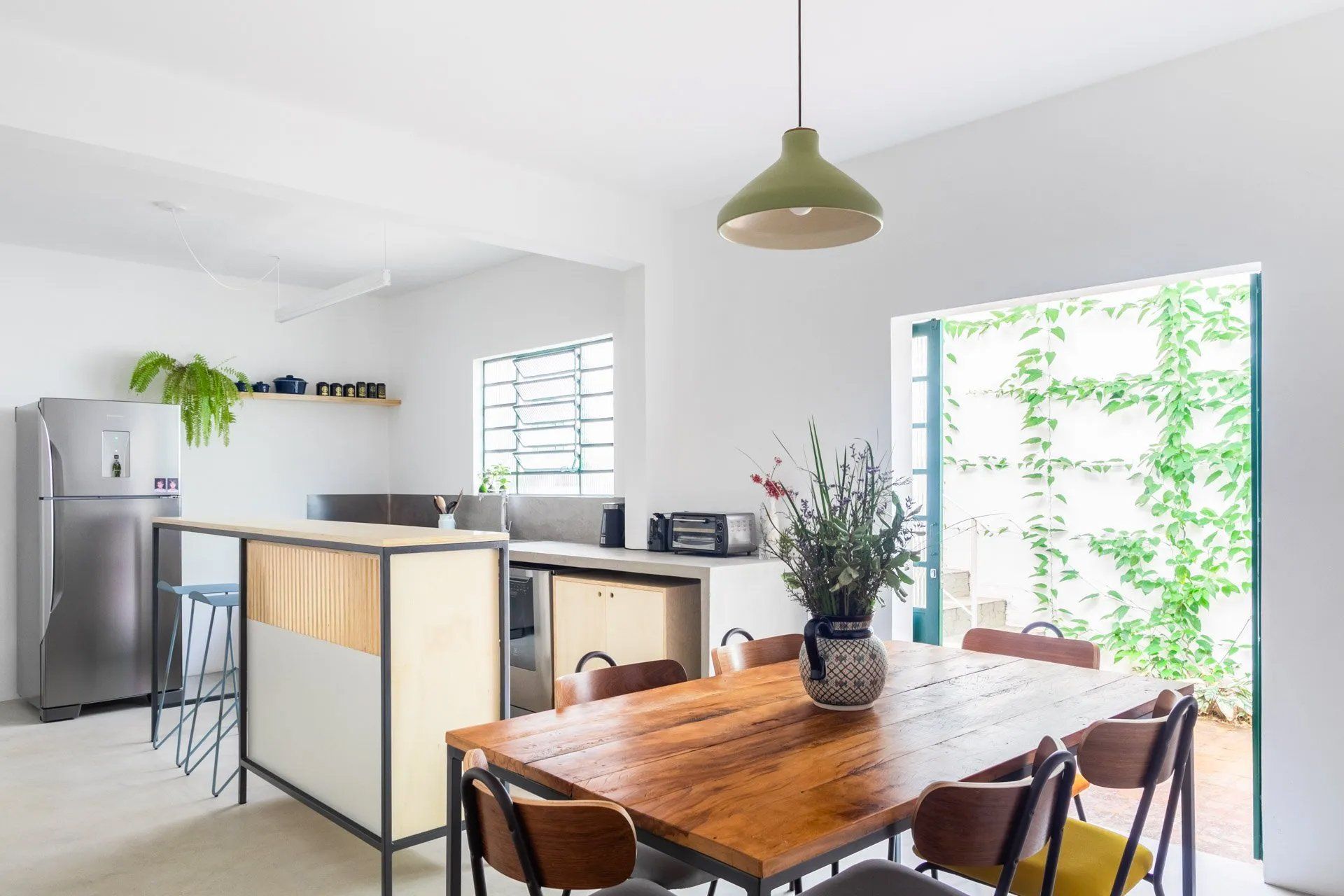 Uma sala de jantar com mesa e cadeiras de madeira e uma geladeira.