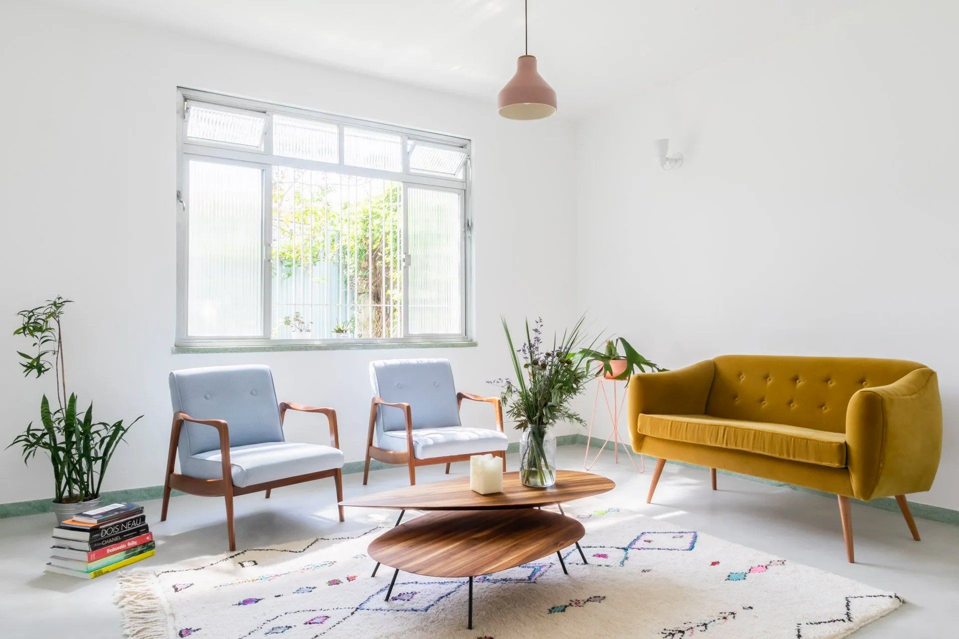 Uma sala com um sofá amarelo, duas cadeiras, uma mesa de centro e uma janela.