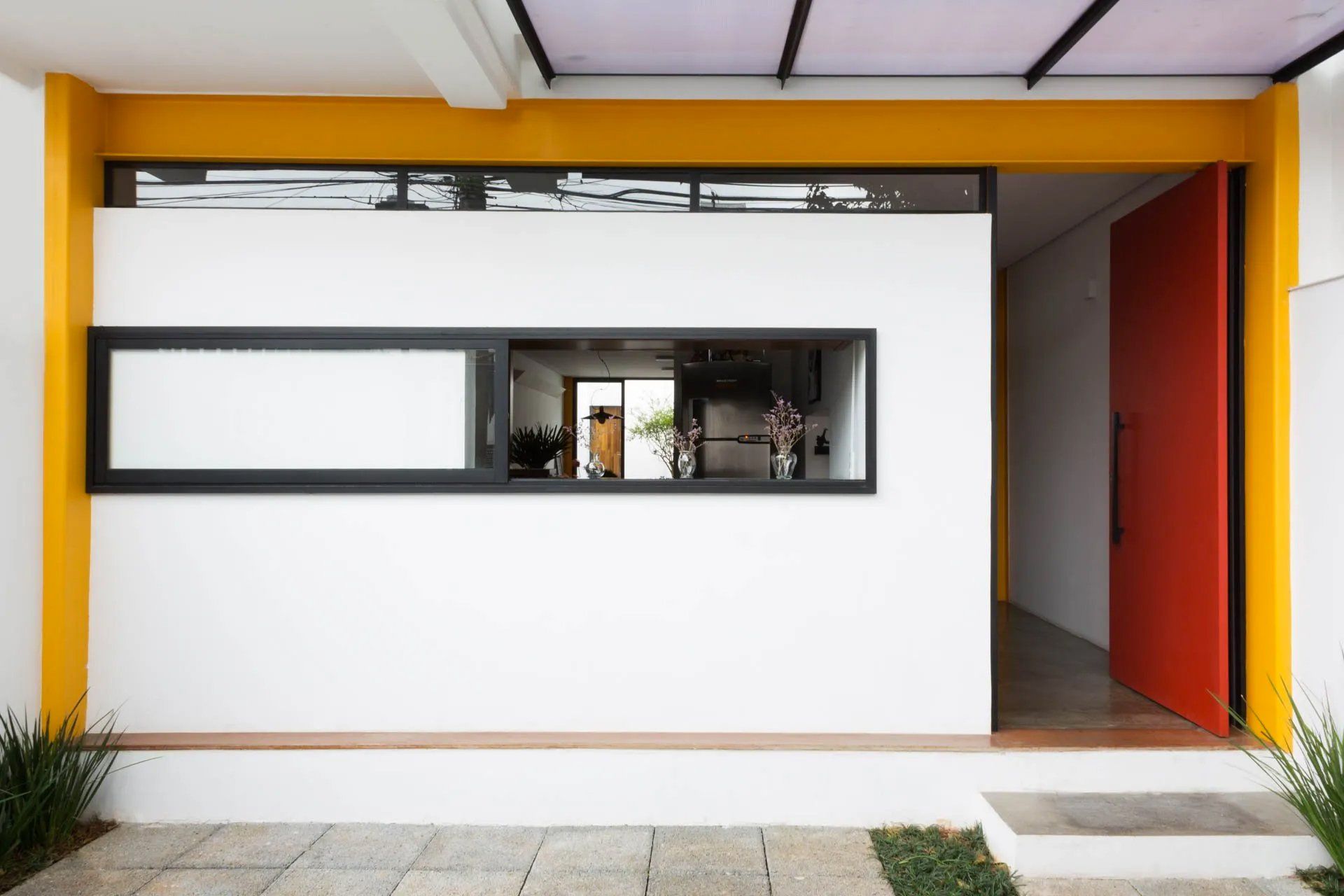 Um prédio branco com porta vermelha e detalhes amarelos