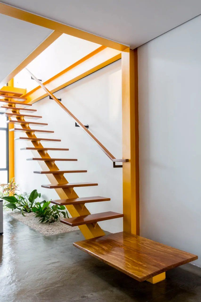 Uma escada de madeira com corrimão amarelo em uma sala