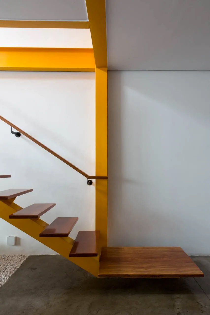 Uma escada amarela com degraus de madeira e corrimão amarelo