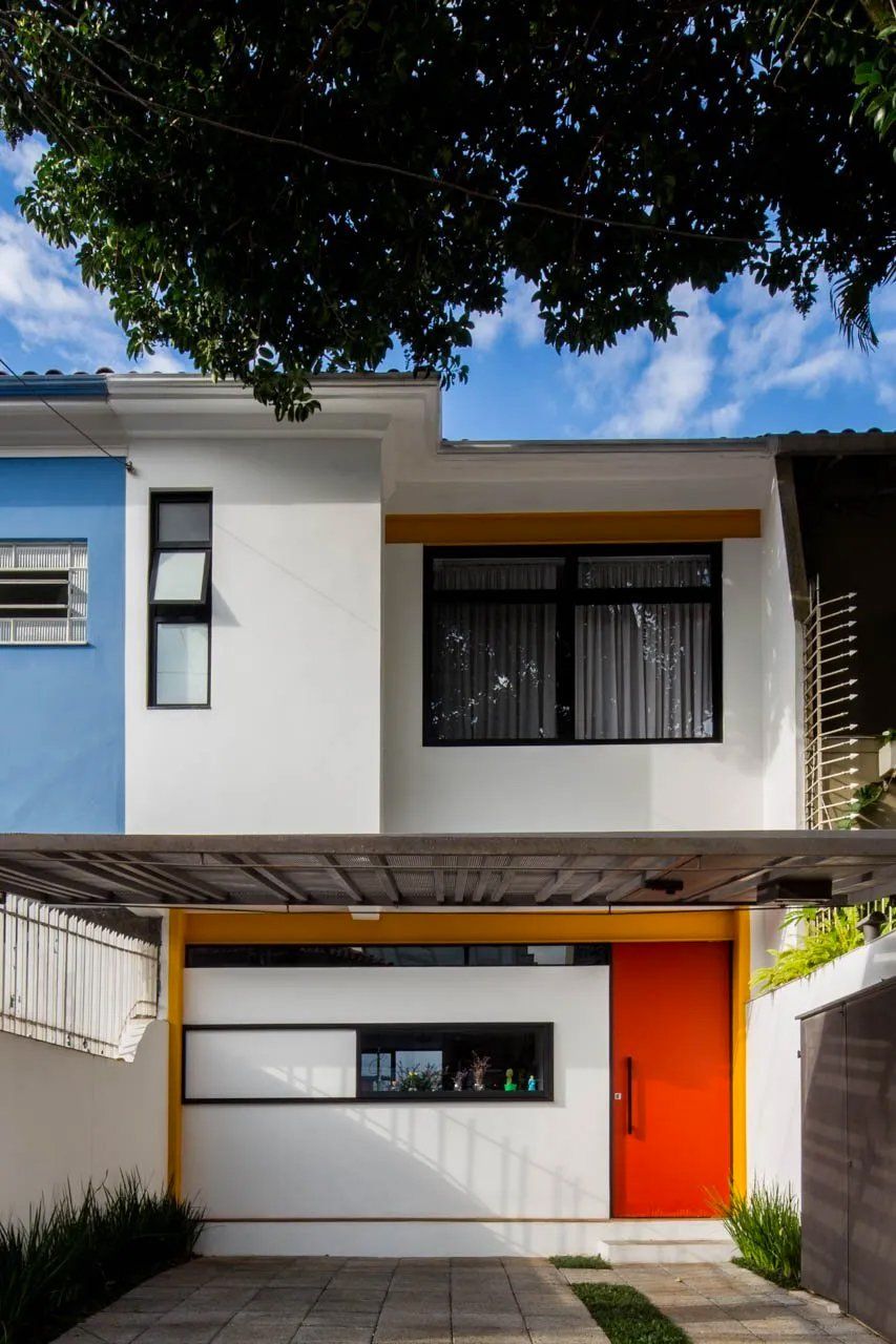 Uma casa azul e branca com porta vermelha