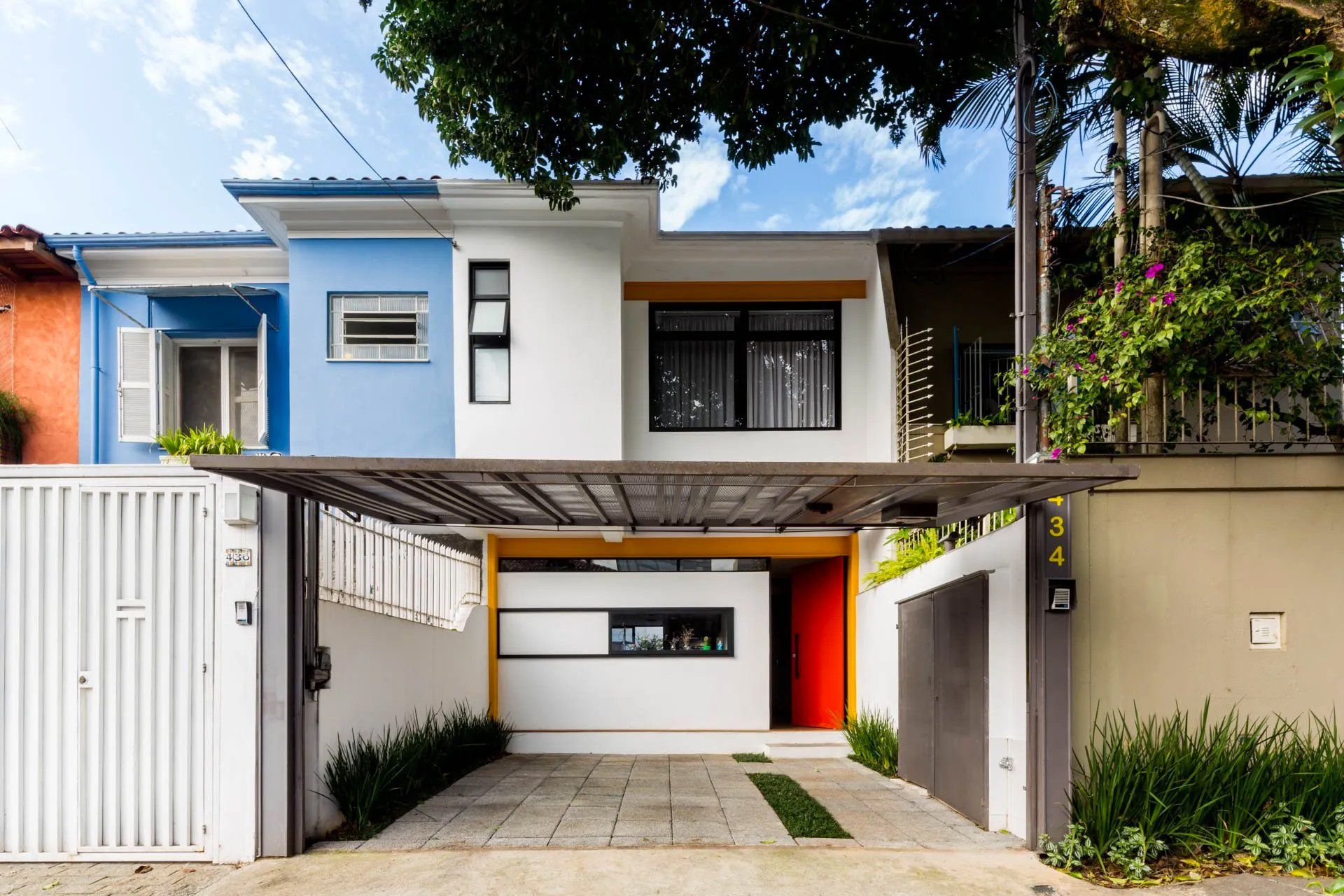 A frente de uma casa com entrada de automóveis e cerca