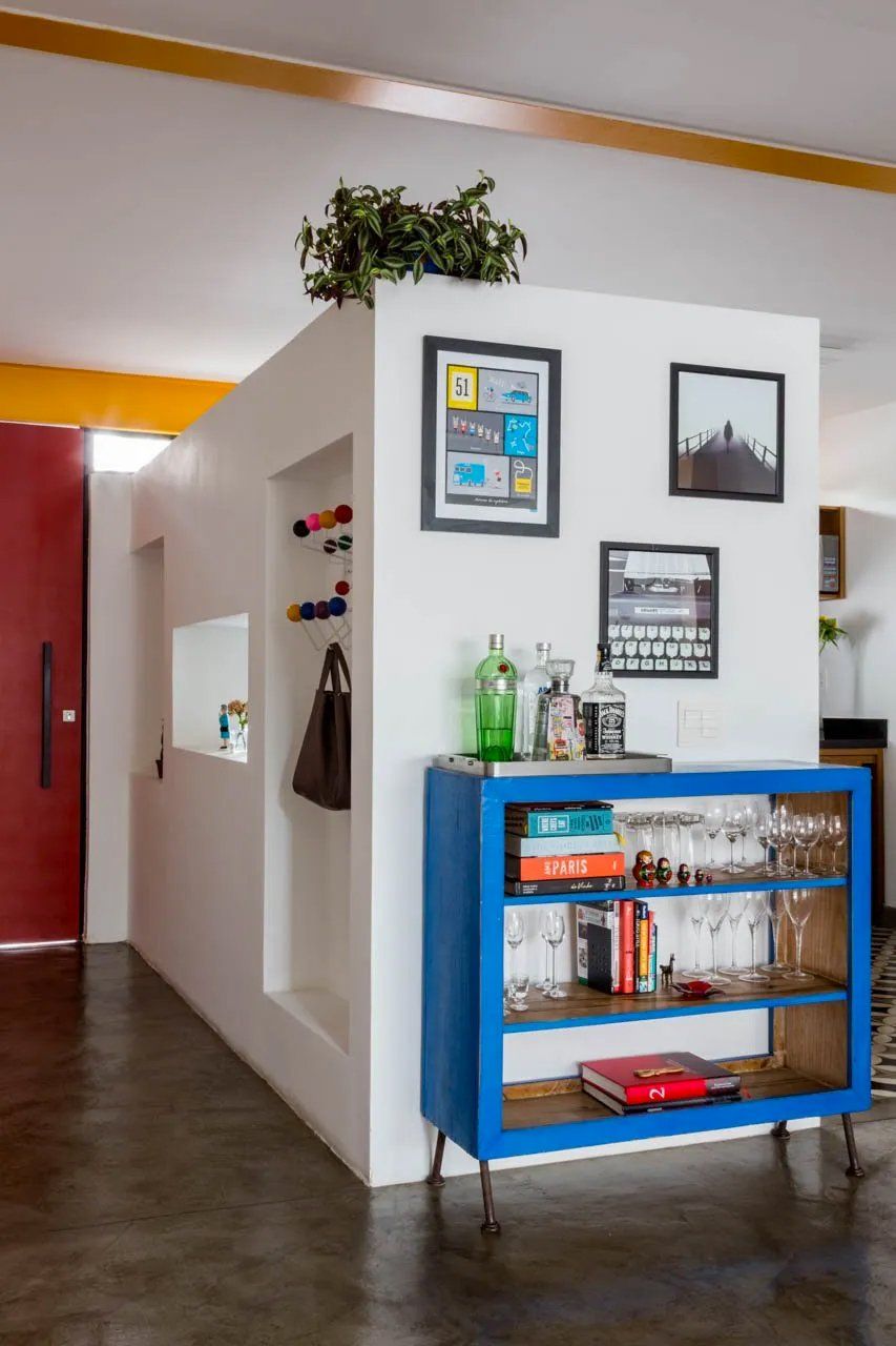 Uma prateleira azul com taças de vinho e livros