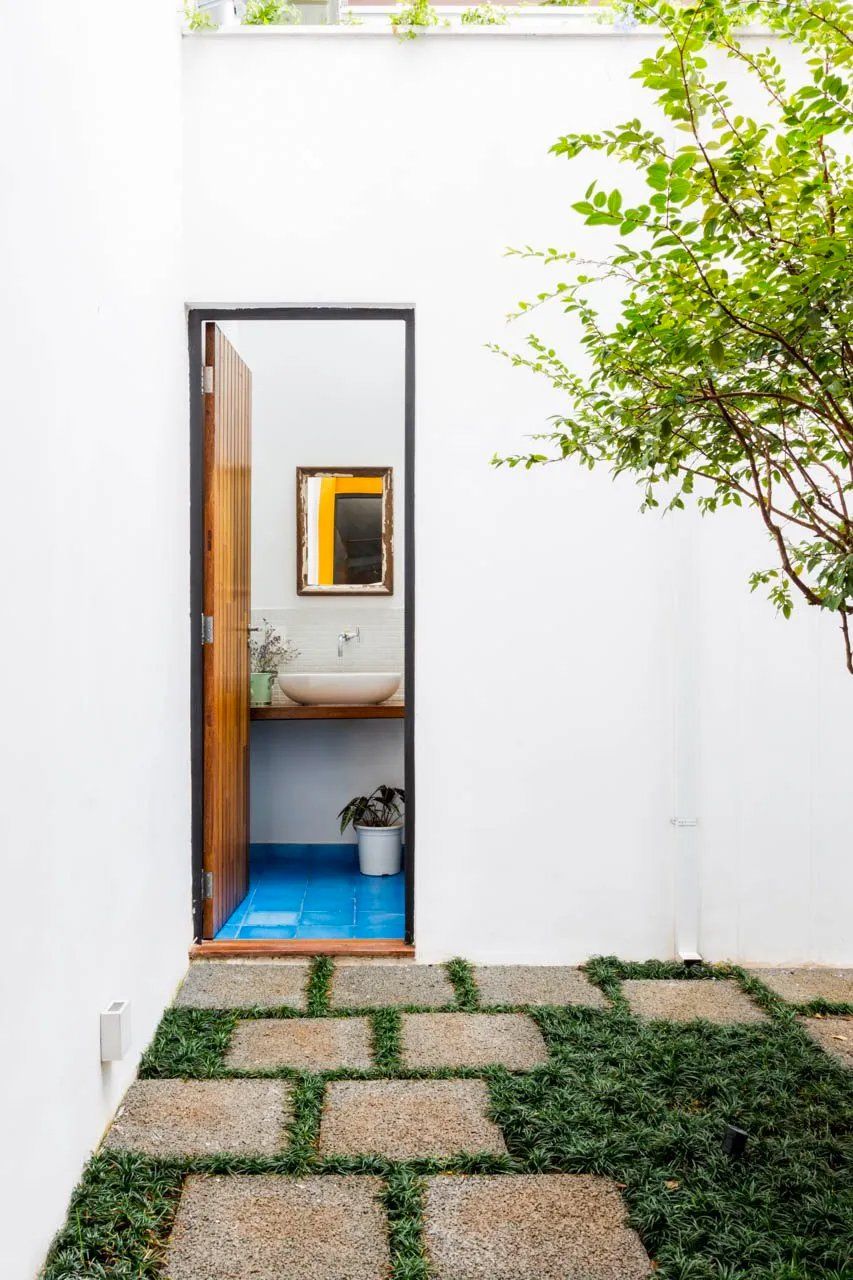 Uma porta que leva a um banheiro com pia e espelho