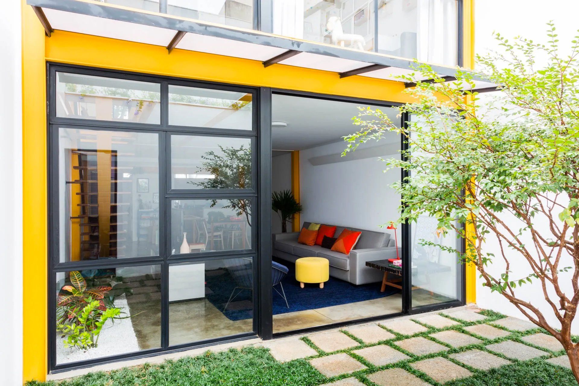 Uma sala com um sofá e uma árvore na frente.