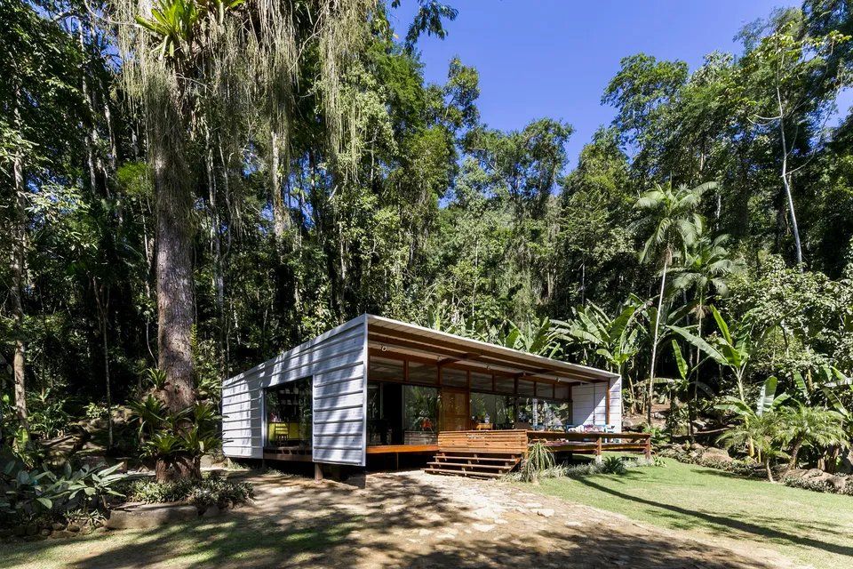 Uma pequena casa está cercada por árvores no meio de uma floresta.