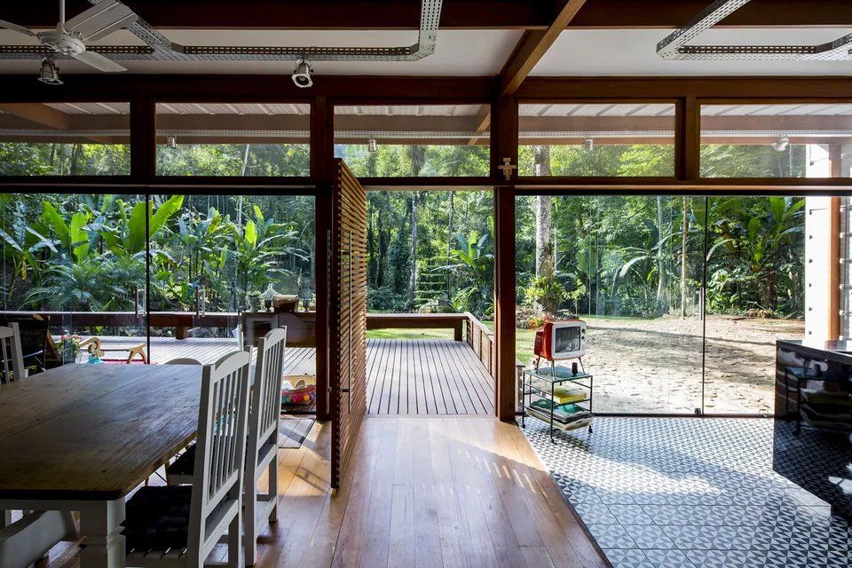 Uma sala de estar com mesa e cadeiras e vista para uma floresta.