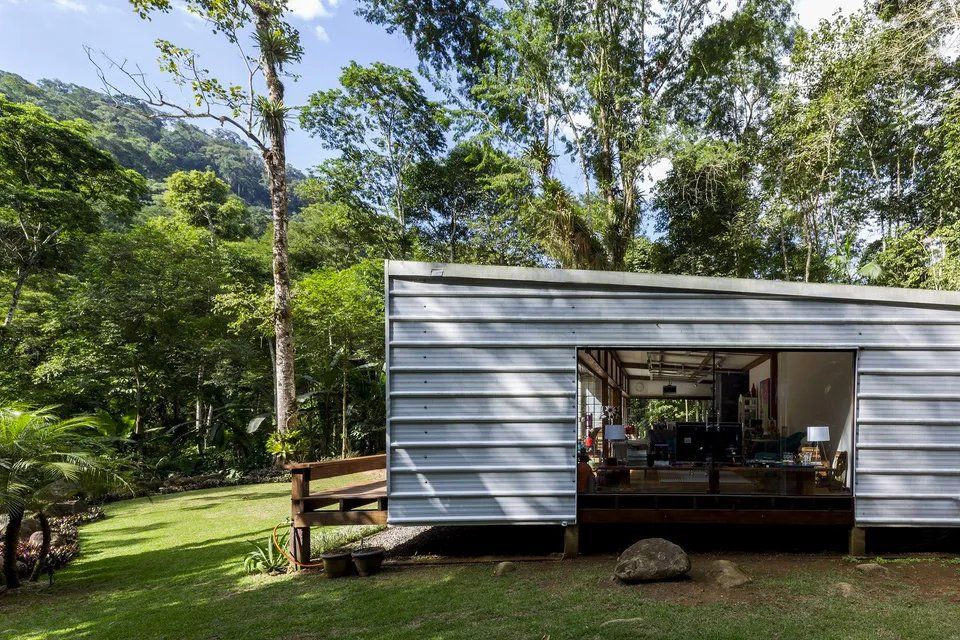 Uma pequena casa está situada no meio de uma floresta verdejante.