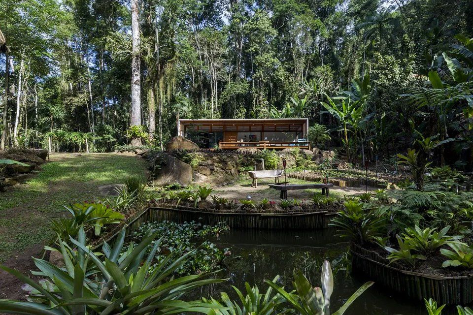 Uma casa no meio de uma floresta com um lago na frente.