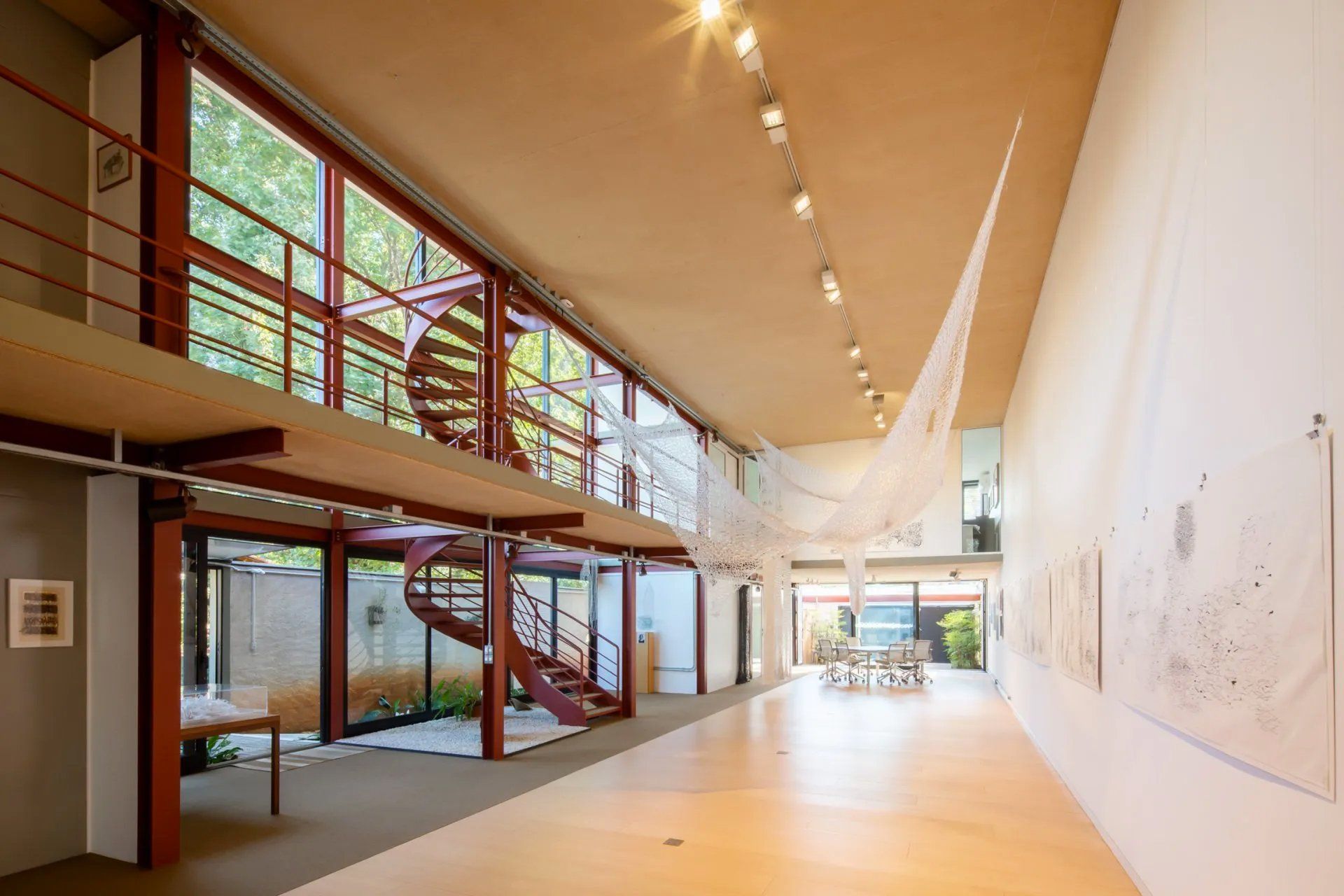 Uma grande sala vazia com uma escada em espiral e muitas janelas.