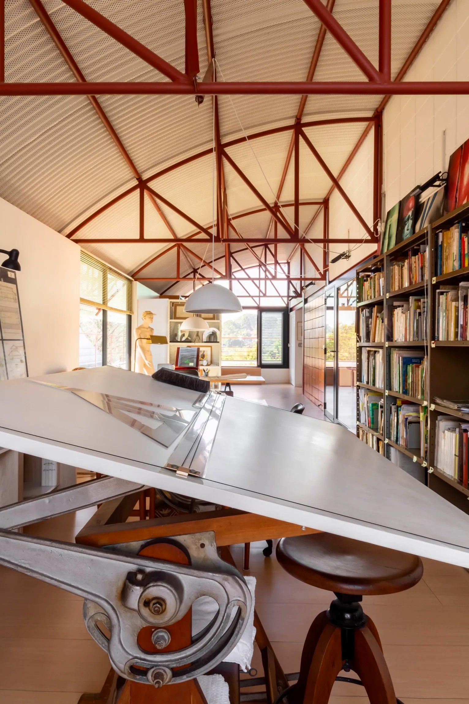 Uma grande mesa branca está em uma sala com estantes de livros.