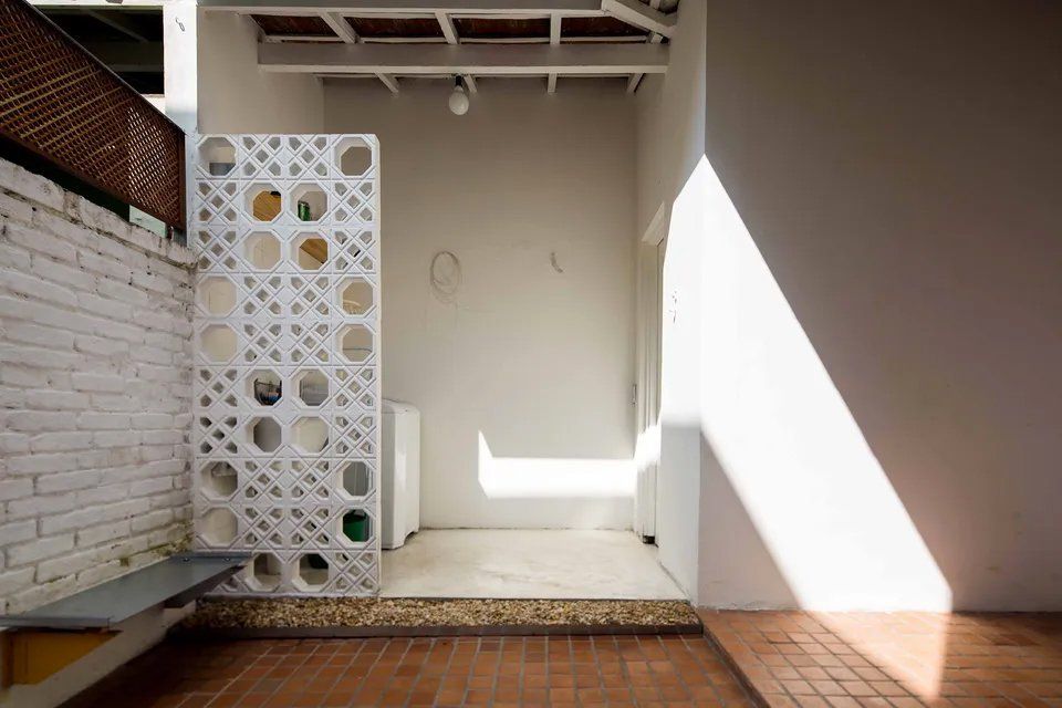 Uma sala com uma parede de tijolos e uma parede branca com buracos.