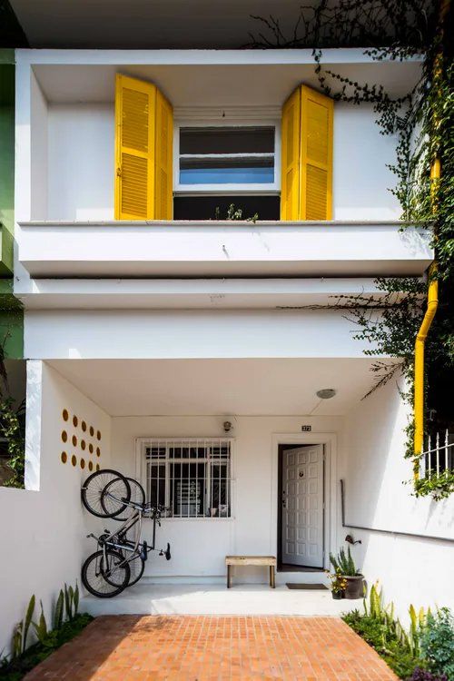 Uma casa branca com venezianas amarelas nas janelas