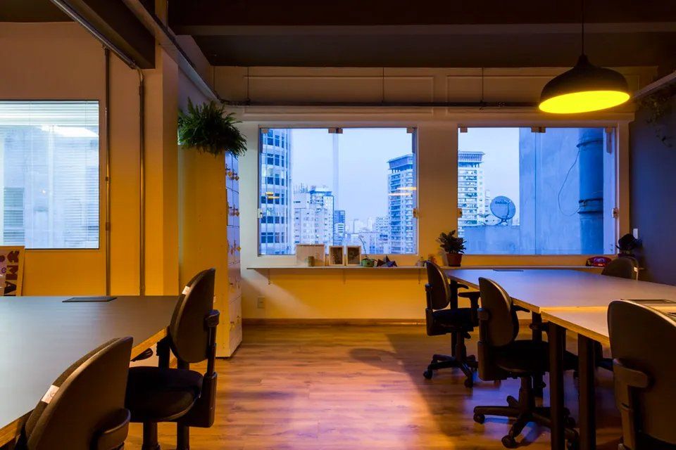 Uma sala com mesas e cadeiras e uma janela com vista para a cidade.