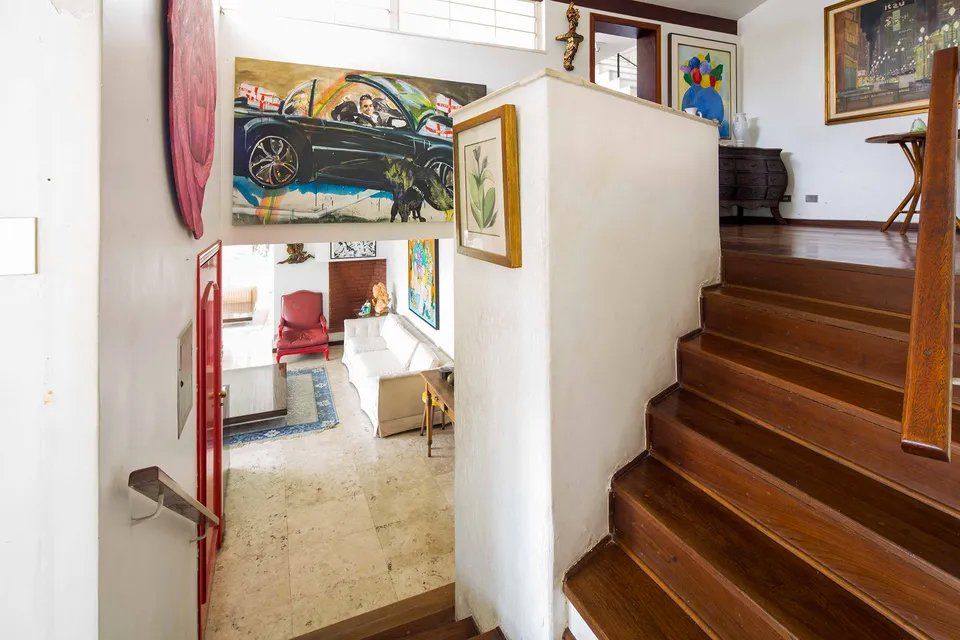 Uma escada de madeira que conduz a uma sala com pinturas na parede.