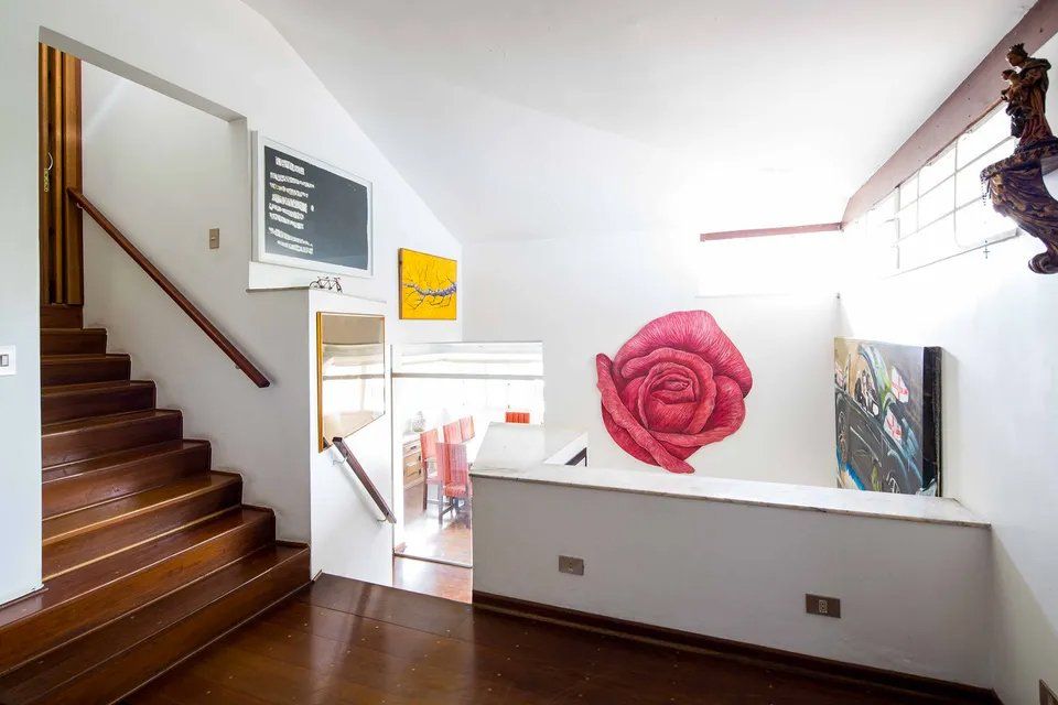 Uma sala com escadas e uma pintura de uma rosa na parede