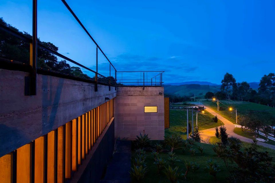 Um prédio com varanda no topo fica iluminado à noite.